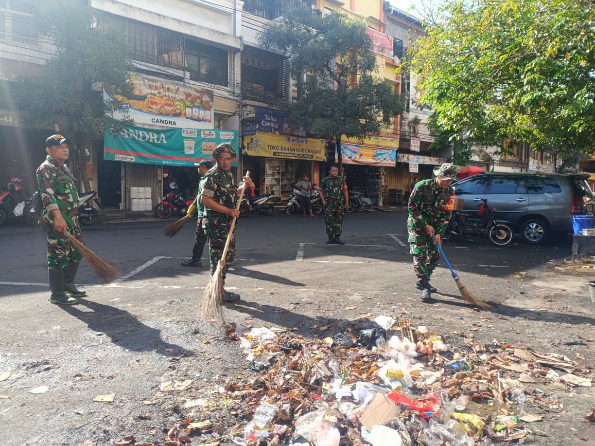 Personel Koramil 0833-01/Klojen menyapu sampah di area Pasar Besar.