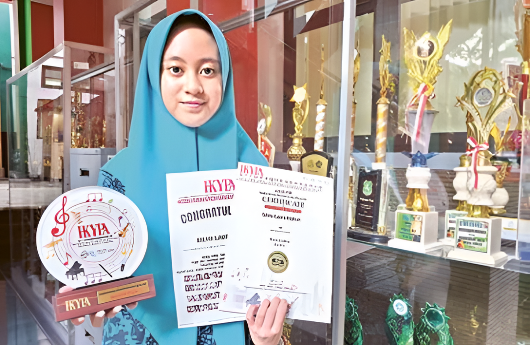 BERPRESTASI: Silmi Laura Hakim, siswi MTsN 1 Kota Malang menunjukkan piagam dan piala prestasi yang diraihnya. (Nabila Amelia/Radar Malang)