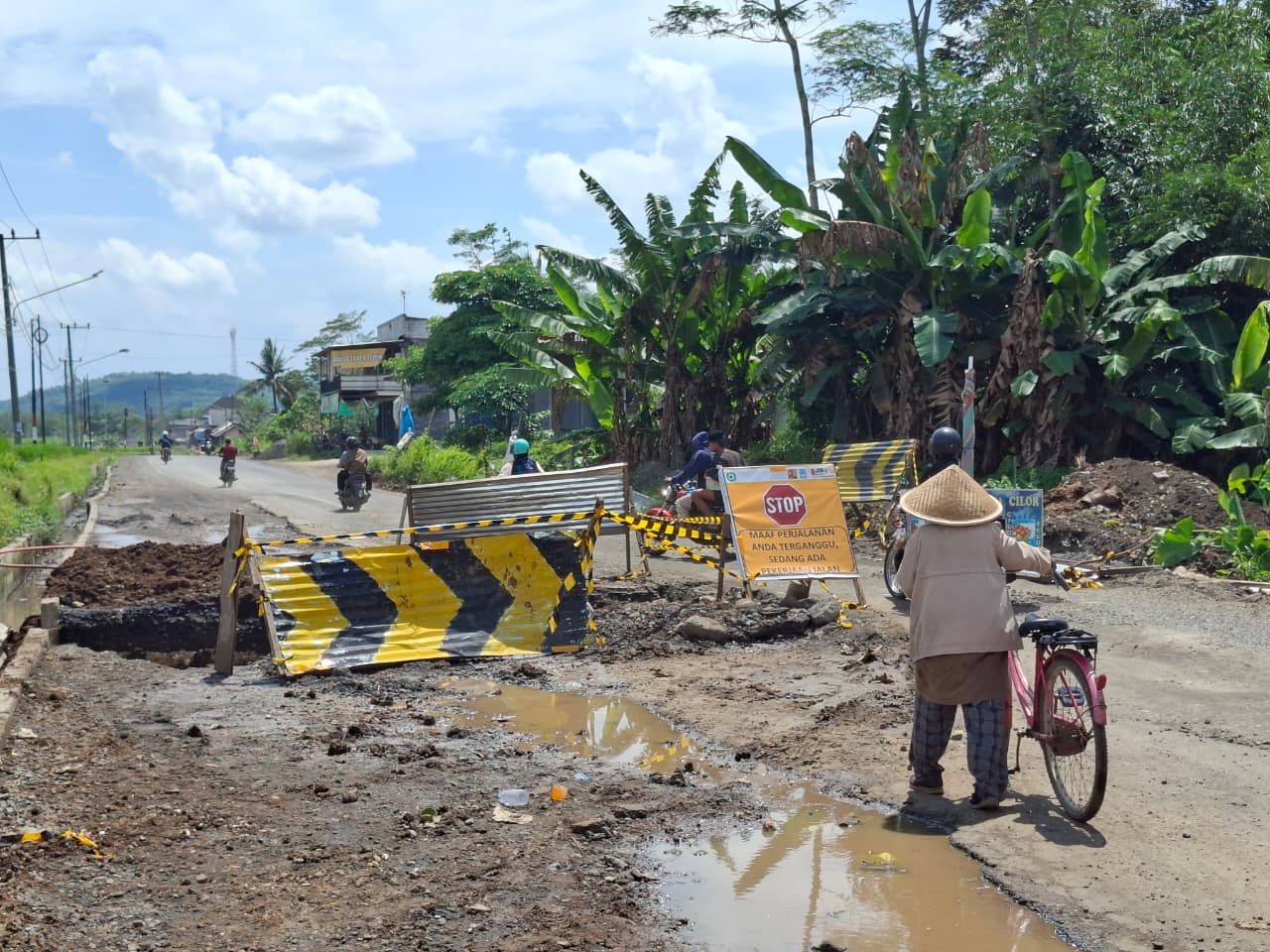 BUTUH PERHATIAN: Pengendara melintas hati-hati di Jalan Gondanglegi-Balekambang yang masih dalam perbaikan dengan lubang galian dan genangan air kemarin. (Biyan Mudzaky Hanindito/ Radar Kanjuruhan)