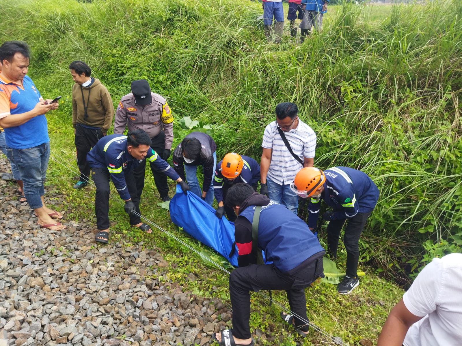 Relawan dan polisi melakukan evakuasi pria yang tewas setelah tertabrak kereta api di Singosari, Selasa (10/2). (Polsek Singosari)