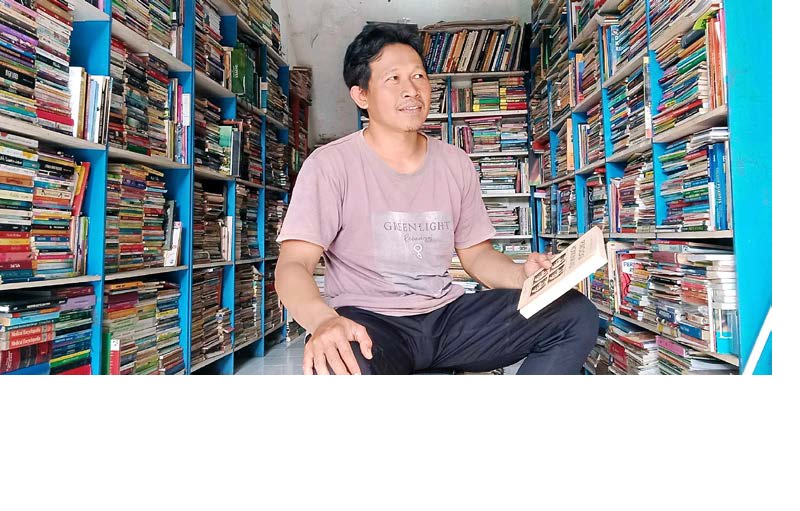 TETAP BERTAHAN: Dodik Irawan tengah merapikan buku di rak tokonya kemarin siang. Dia adalah satu dari 15 pedagang di Pasar Buku Velodrome yang tetap bertahan.