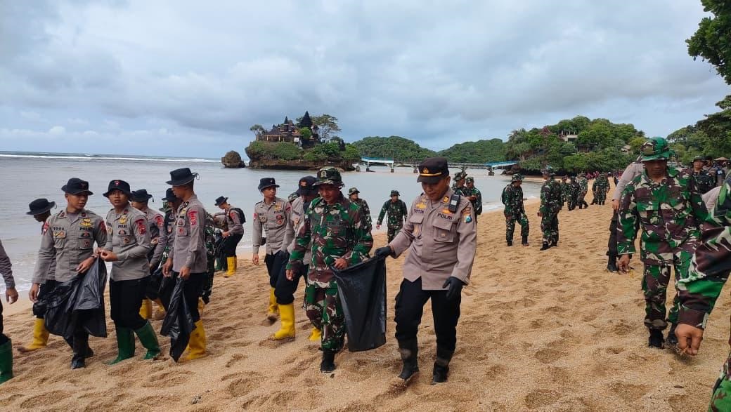 DIJAGA BERSAMA: Personel TNI dan Polri bekerja sama memungut sampah di Pantai Balekambang, kemarin pagi (13/2). Total 421 orang yang ikut dalam kegiatan itu. (Humas Polres Malang for Radar Kanjuruhan)