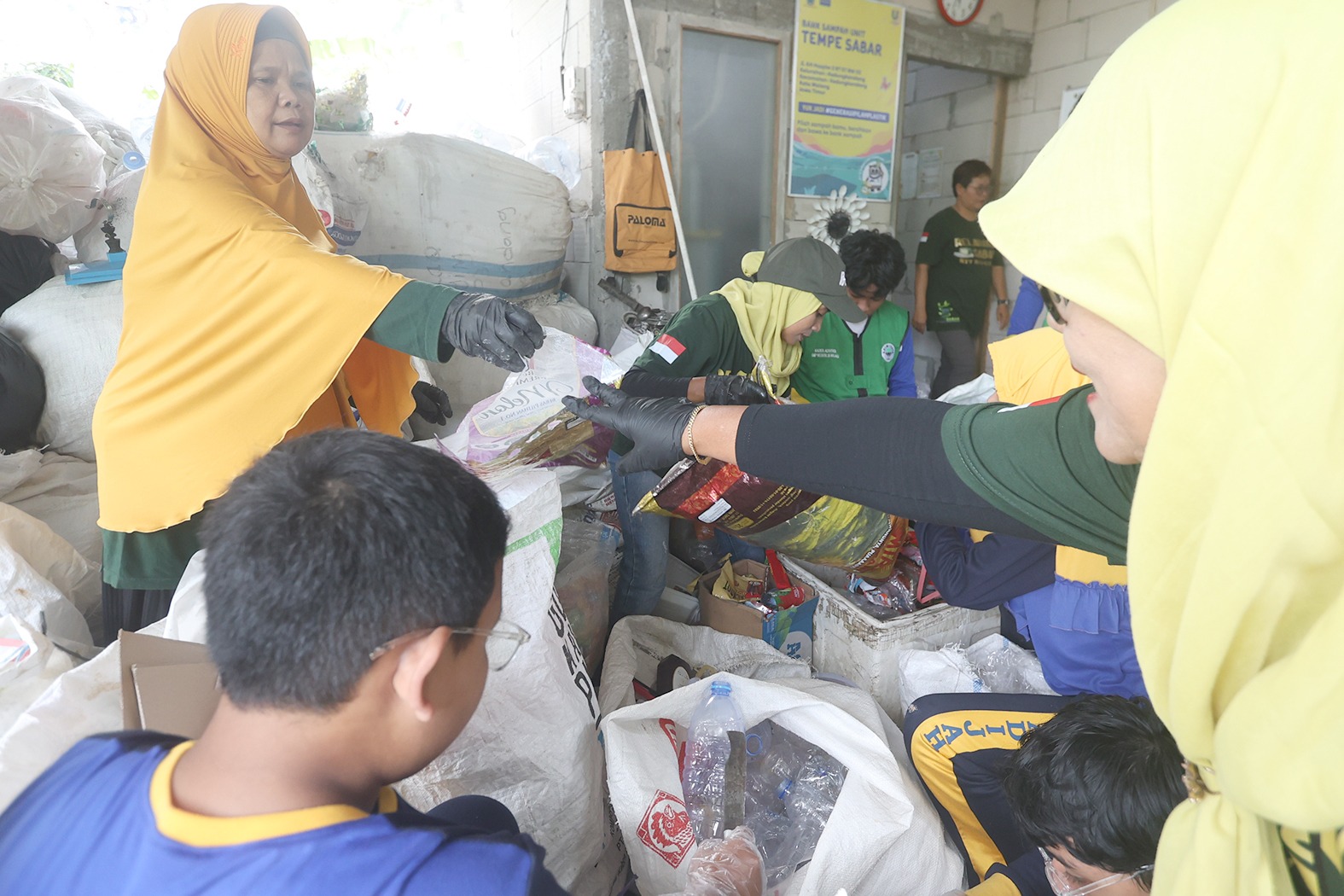 JAGA KEBERSIHAN: Beberapa warga berkolaborasi memisahkan berbagai jenis sampah di Tempat Pemilah Sampah Barokah, Kedungkandang, kemarin. (Darmono/Radar Malang)