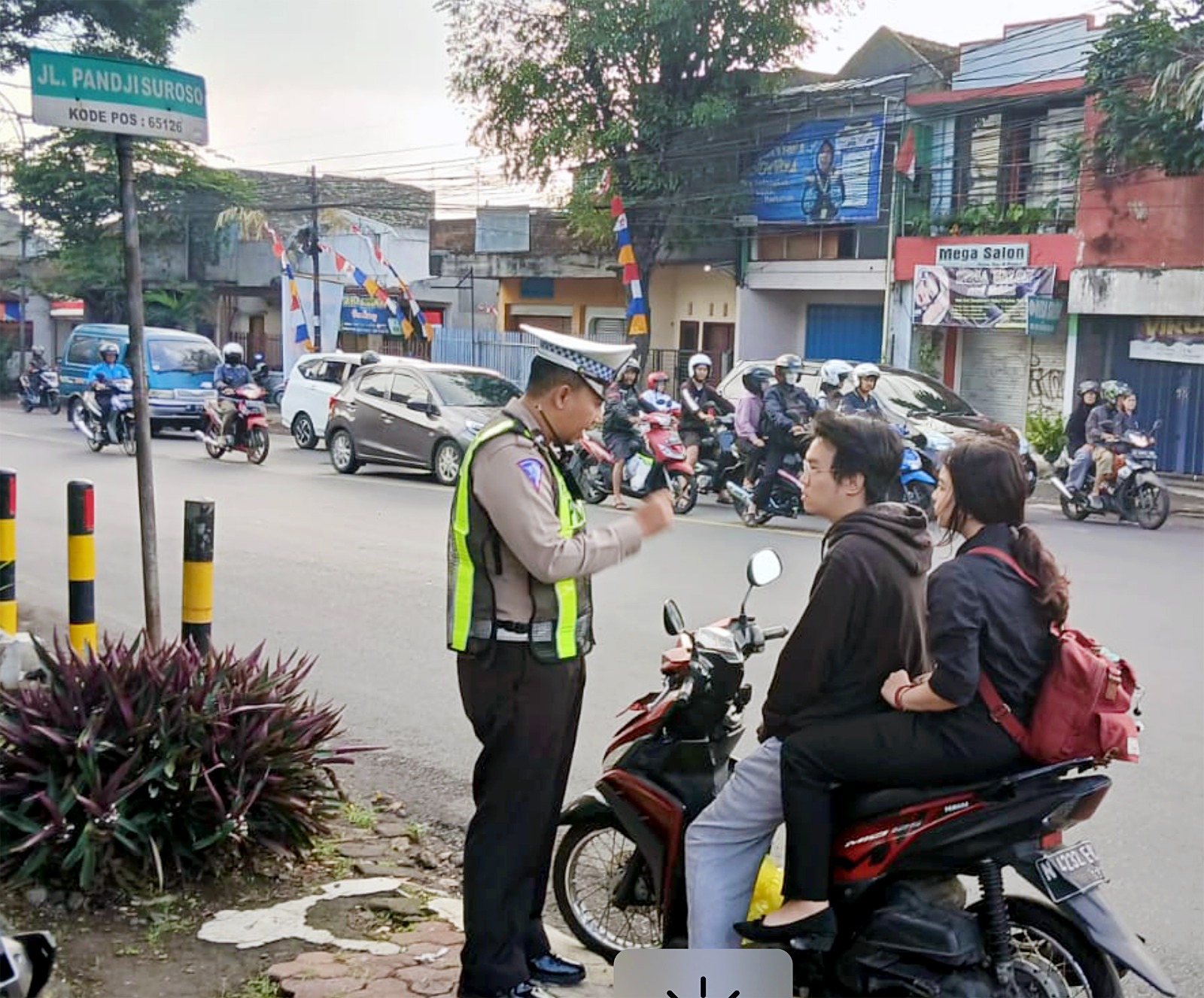 TEGURAN SIMPATIK: Petugas menghentikan dua remaja yang tidak mengenakan helm di Jalan Pandji Suroso, Blimbing kemarin.