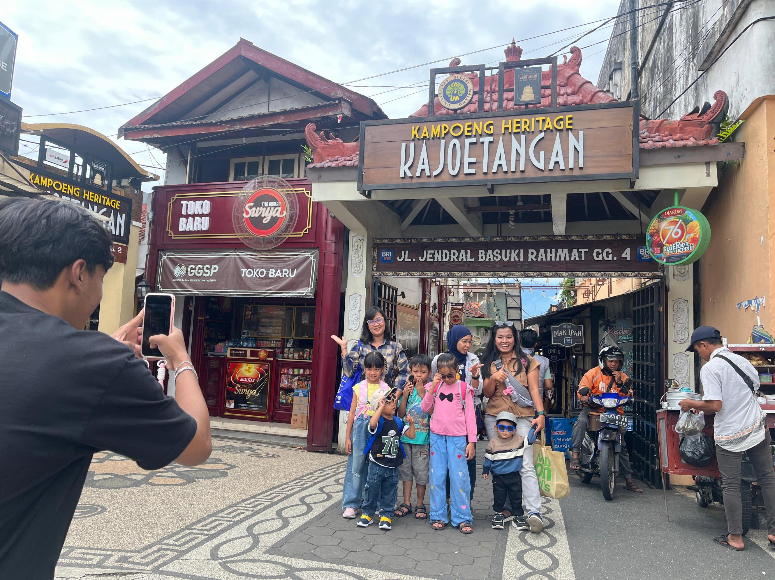 PUNYA DAYA TARIK: Wisatawan berfoto di pintu masuk Kampung Heritage Kajoetangan kemarin siang. Sejak Sabtu (14/2) lalu, Kampung Heritage Kajoetangan panen jumlah wisatawan.
