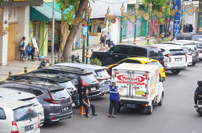 PARKIR KHUSUS: Juru parkir bersantai di sela menata kendaraan di ruas Jalan Basuki Rahmat kemarin (19/2). Area ini steril sepeda motor sejak Pemkot Malang membangun gedung parkir.