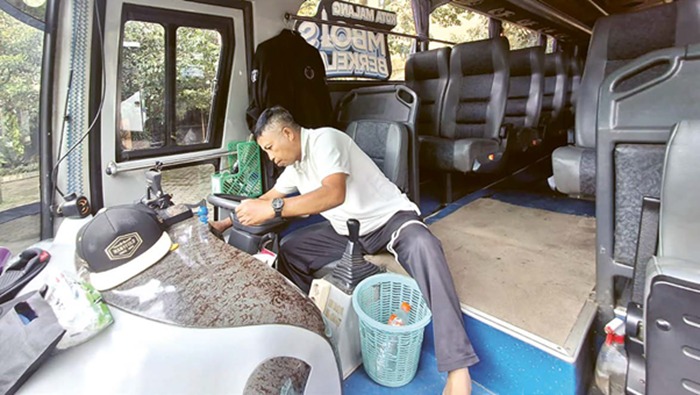 TUNGGU KEPASTIAN: Seorang sopir bus Halokes memanaskan mesin armada sebelum menjemput pelajar kemarin pagi. Operasional layanan bus Halokes masih berjalan sambil menanti terbitnya perwal tentang