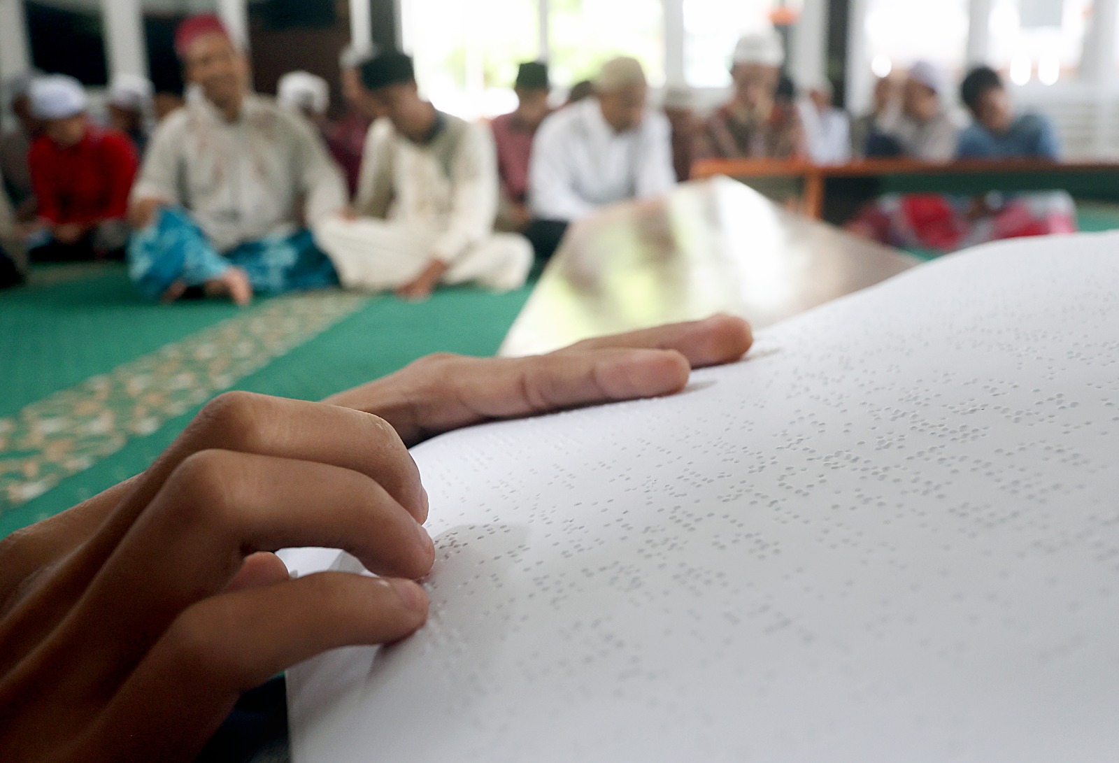 AKTIVITAS: Salah satu disabilitas netra membaca Al-Quran huruf braille.