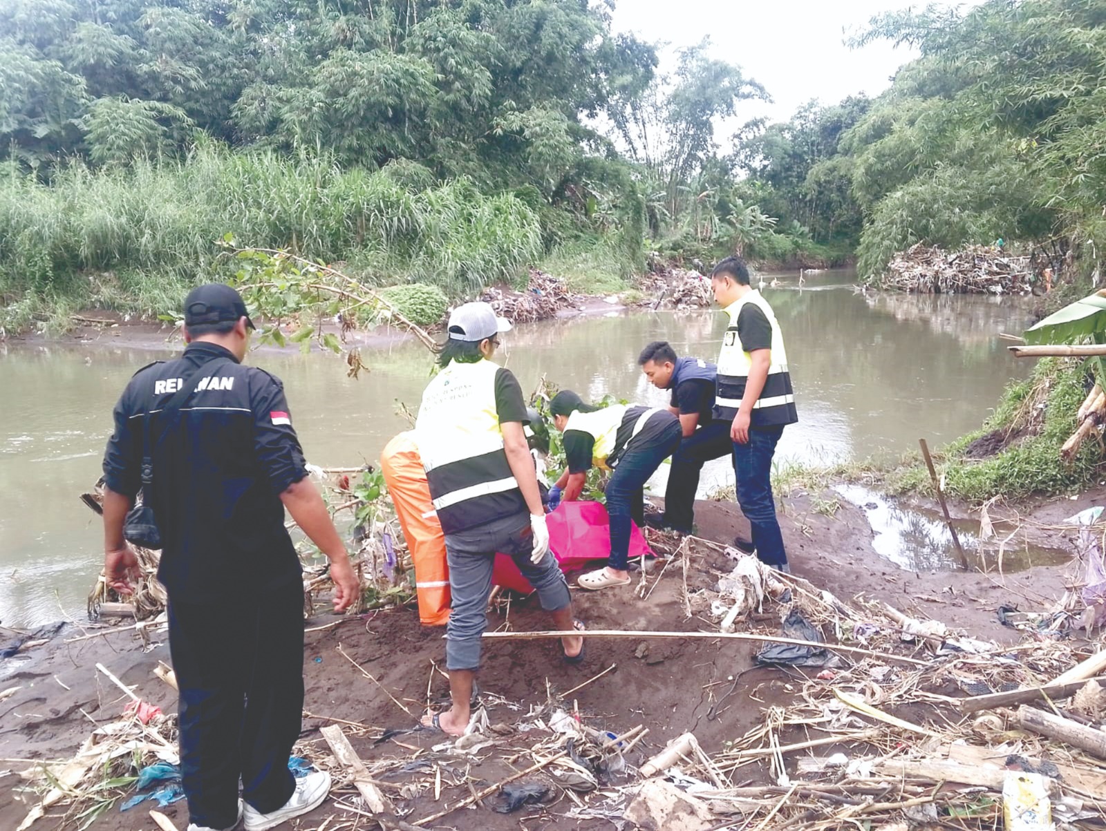 CARI PELAKUNYA: Petugas kepolisian bersama relawan mengevakuasi jasad bayi yang ditemukan warga di tepi Sungai Kalisari, Kelurahan Pandanwangi, Kecamatan Blimbing, Rabu (25/2).
