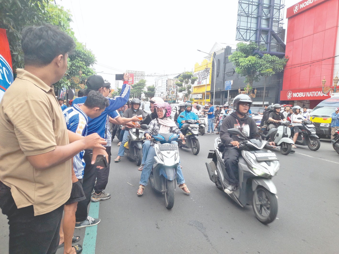 BERBAGI: Para pengendara yang melintas di Kajoetangan Heritage mendapatkan takjil dan nasi kotak dari Aremania, Minggu lalu (1/3).