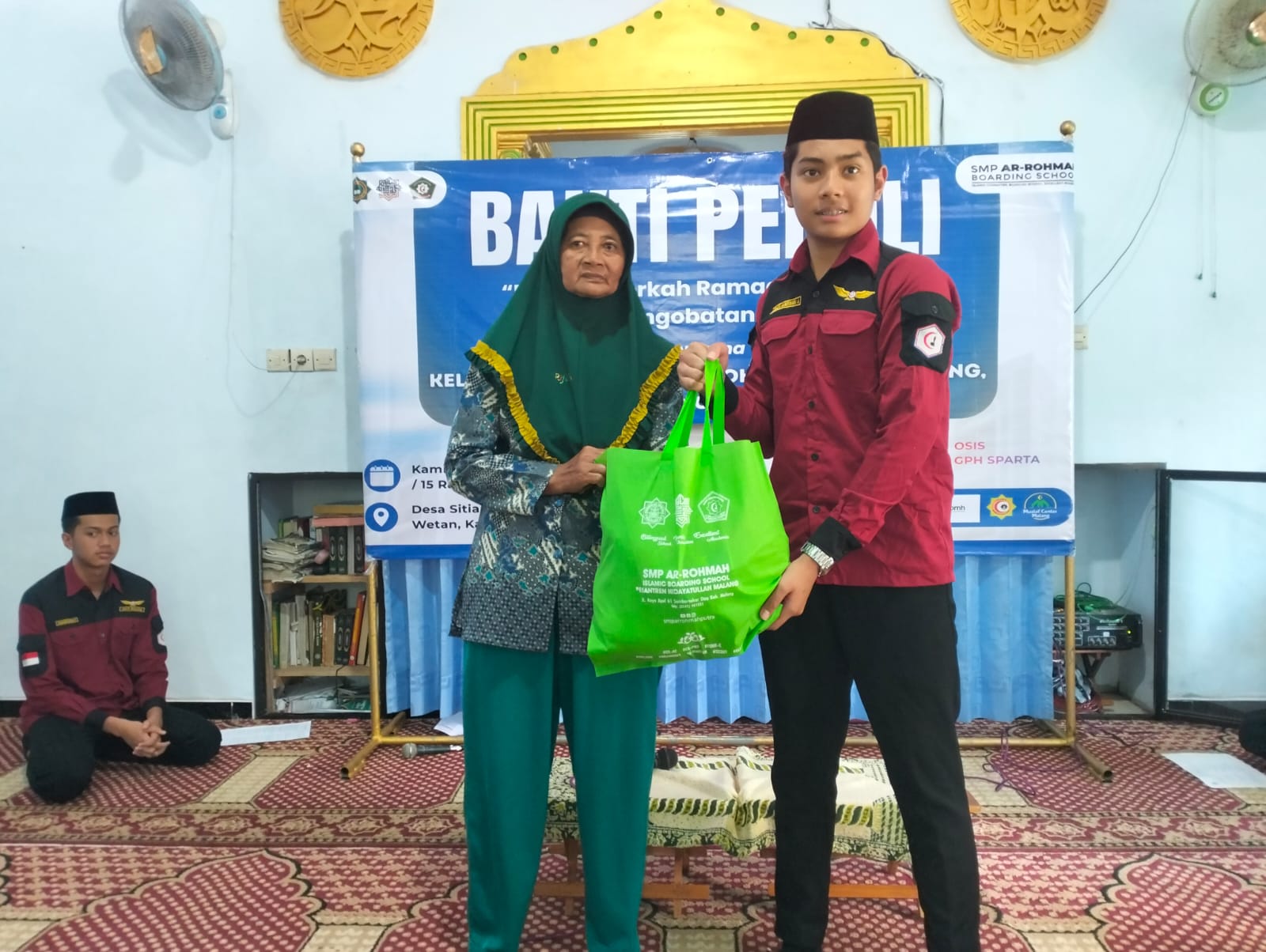BERBAGI : Santri Ketua OSIS SMP Arrohmah menyerahkan bantuan simbolis kepada warga kurang mampu di Kabupaten Malang.