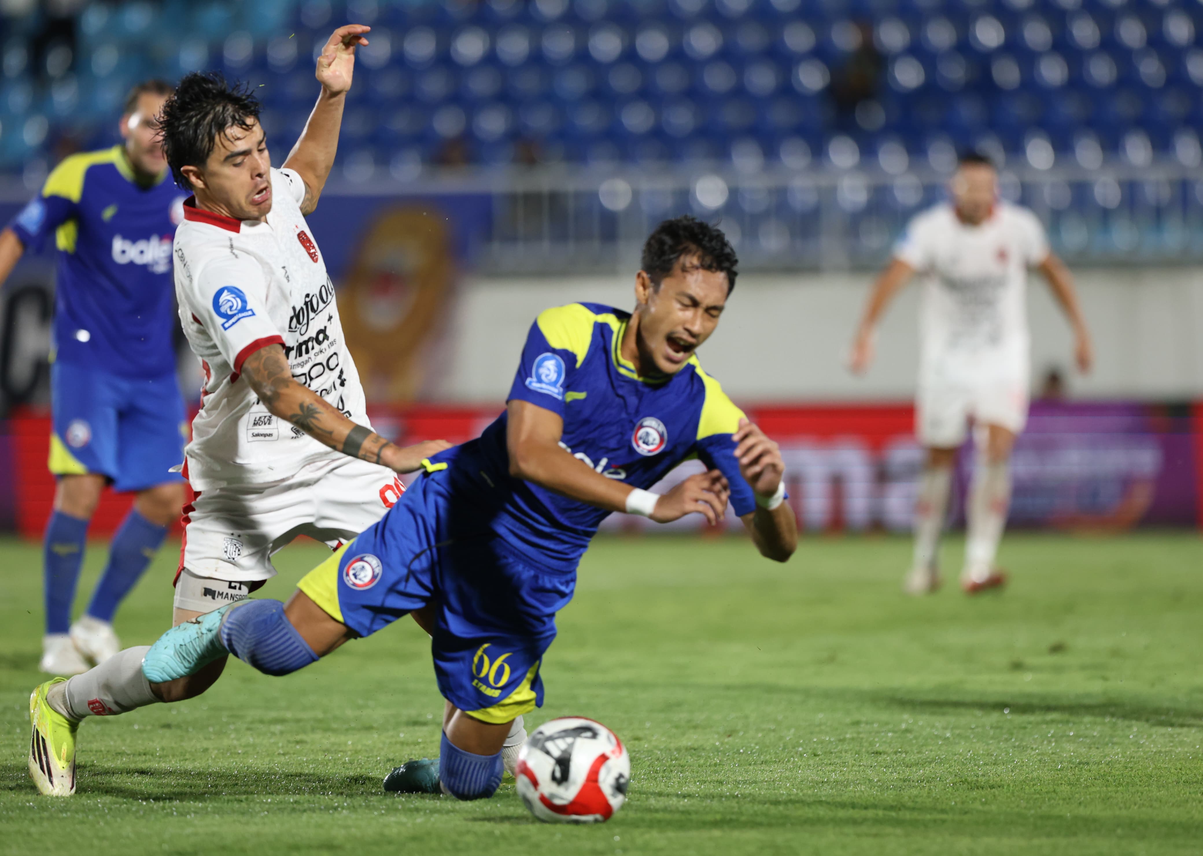Bek Arema FC Hansamu Yama Pranata terjatuh setelah berduel dengan pemain Bali United Diogo Campos di Stadion Kanjuruhan, Jumat (6/3) malam. (Darmono/Radar Malang)