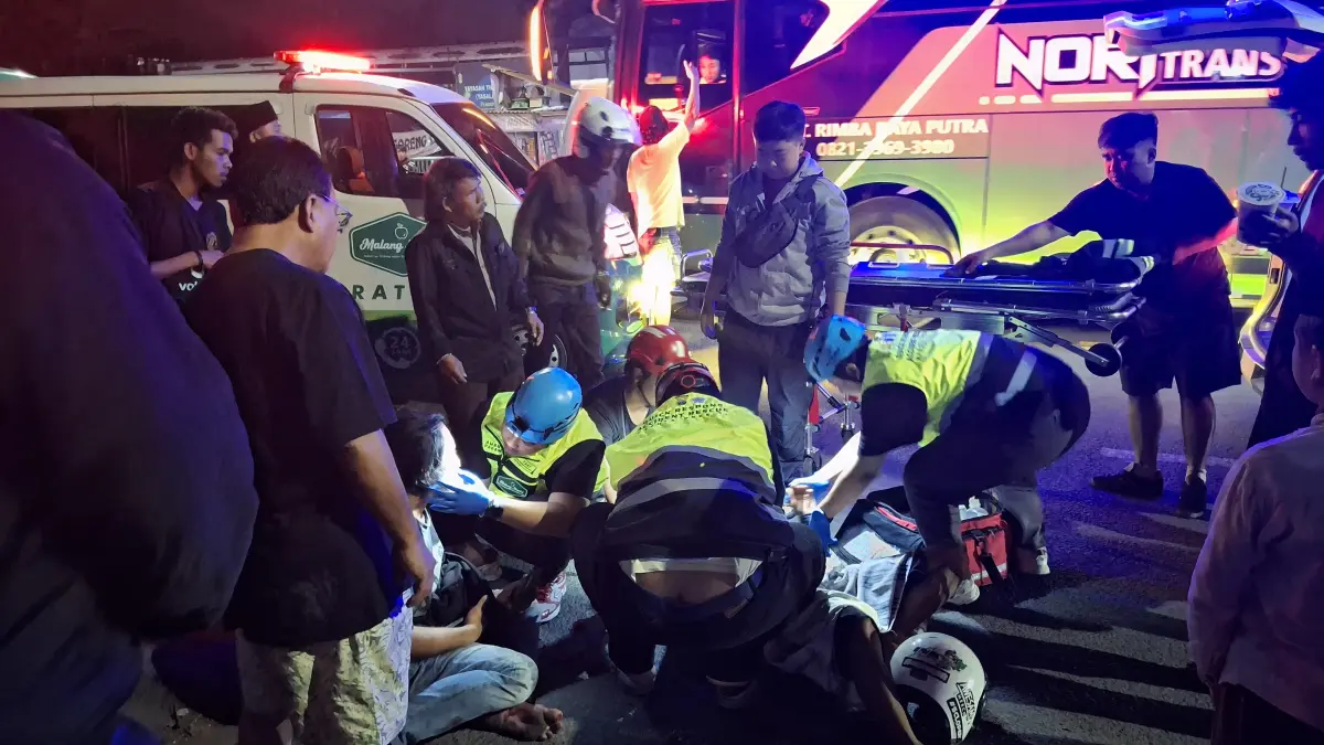 Relawan mengevakuasi korban kecelakaan yang melibatkan sepeda motor vs mobil di Jalan Sunandar Priyo Sudarmo, Jumat (13/3) malam. (Nabila Amelia/Radar Malang)