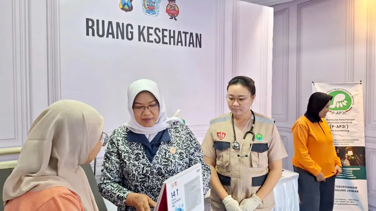PASTIKAN AMAN: Petugas kesehatan yang berjaga di pos pengamanan memberi sosialisasi kepada salah satu warga, kemarin (16/3). (NABILA AMELIA / RADAR MALANG)