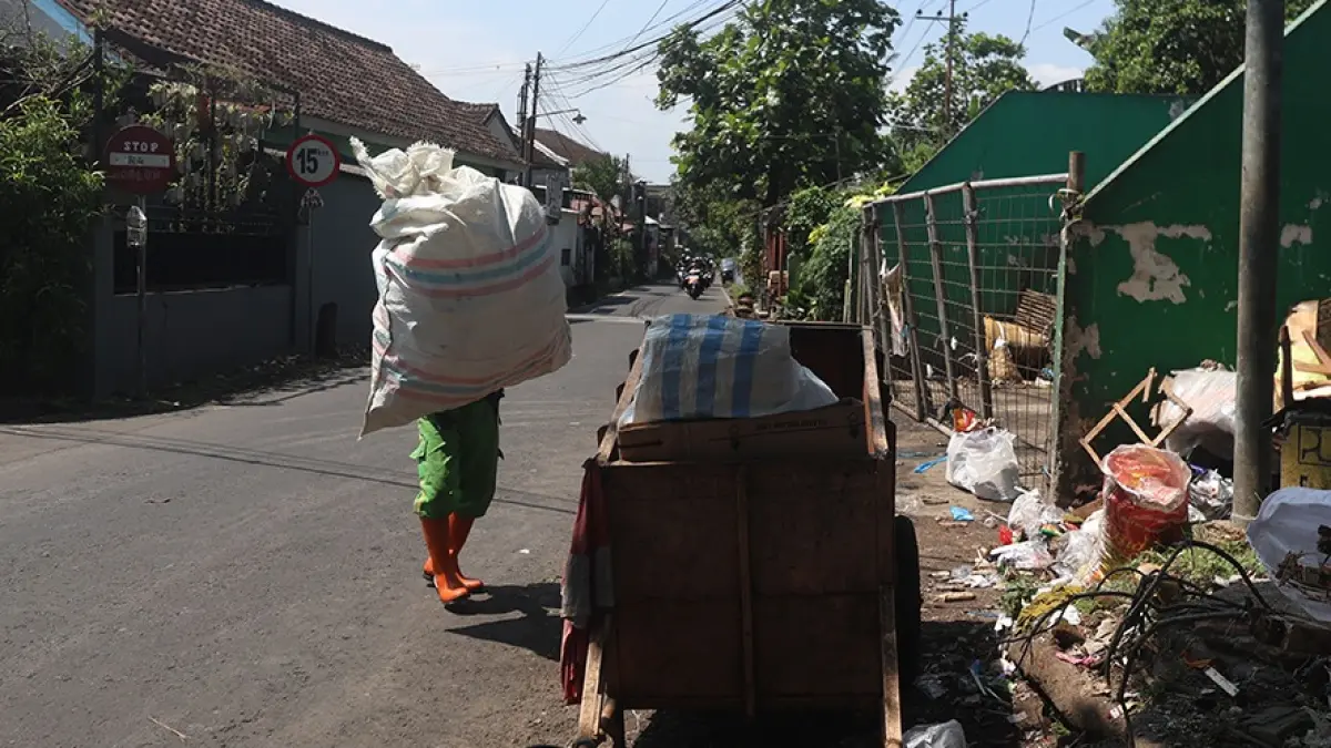 EFEK MAHASISWA MUDIK: Salah satu petugas kebersihan mengangkat sampah di TPS Mergan, Kota Malang, beberapa waktu lalu. DARMONO/RADAR MALANG