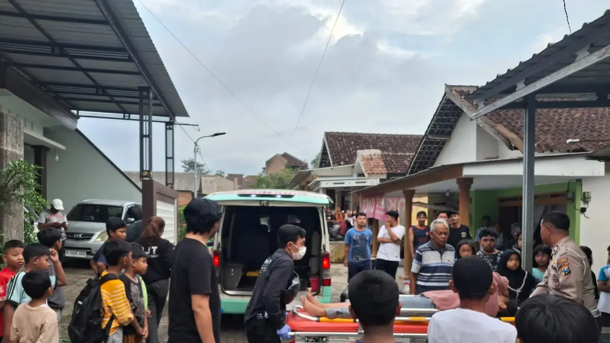 Warga menyaksikan seorang pemilik kos di Buring, Kedungkandang, dibawa menuju ambulans setelah ditusuk oleh penghuni gara-gara tak terima ditegur pada Rabu (1/4). (Polsek Kedungkandang)