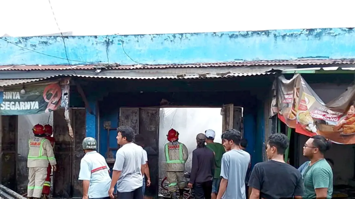 KORSLETING: Petugas Damkar Kabupaten Malang berupaya memadamkan sisa-sisa api dari salah satu kios di Pasar Landungsari, kemarin siang. 