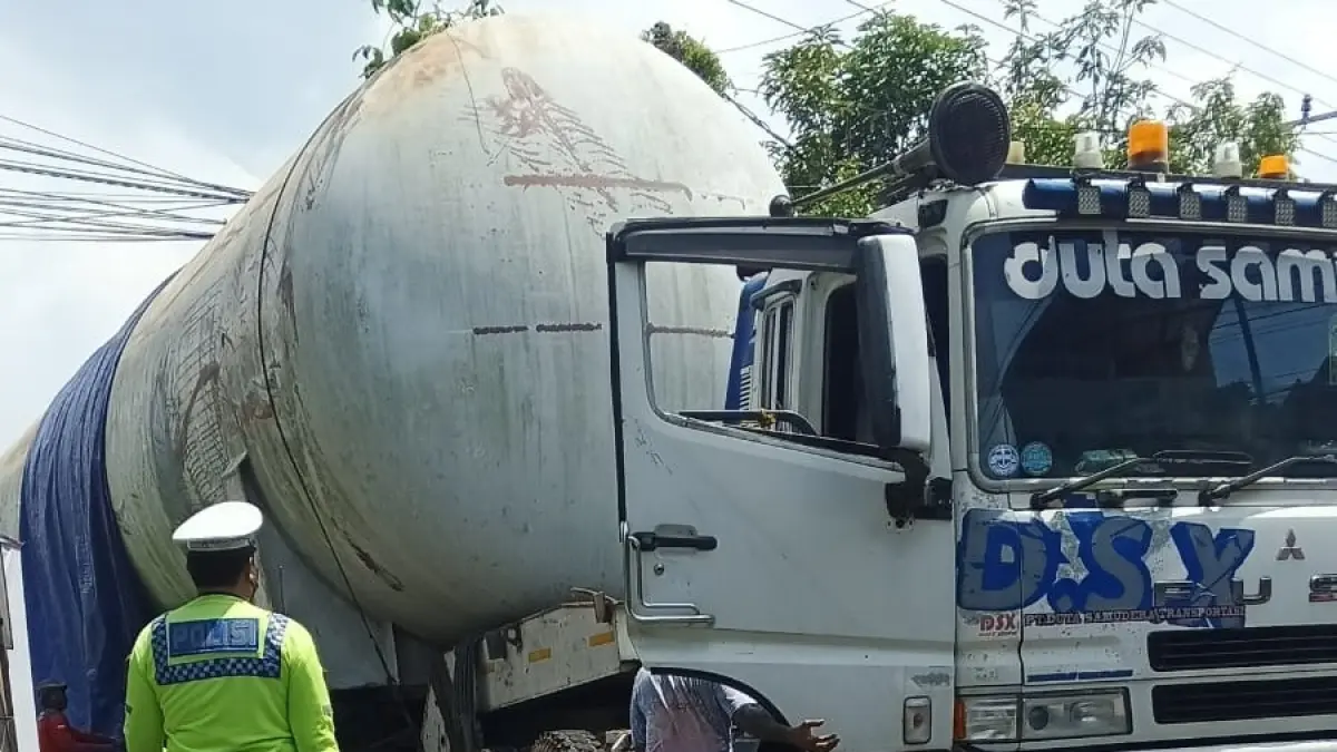 SIAGA: Personel Satlantas Polres Malang mengarahkan pengemudi truk tangki berisi LPG yang terperosok di Kepuharjo, Kecamatan Karangploso kemarin (6/4).