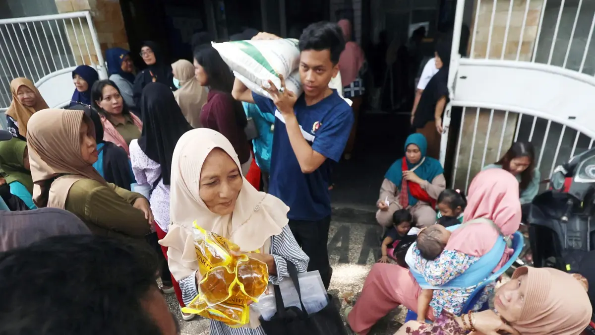 NTUSIASME: Warga yang sudah antre berjam-jam di Kantor Kelurahan Kiduldalem, Kecamatan Klojen akhirnya pulang membawa beras dan minyak goreng kemarin (7/4).