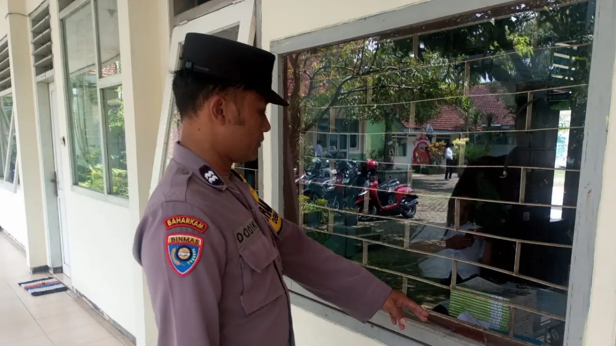 PELAKU DIBURU: Polisi menunjukkan jendela salah satu ruang di SMPN 1 Pakisaji yang dicongkel pelaku kemarin (8/4).