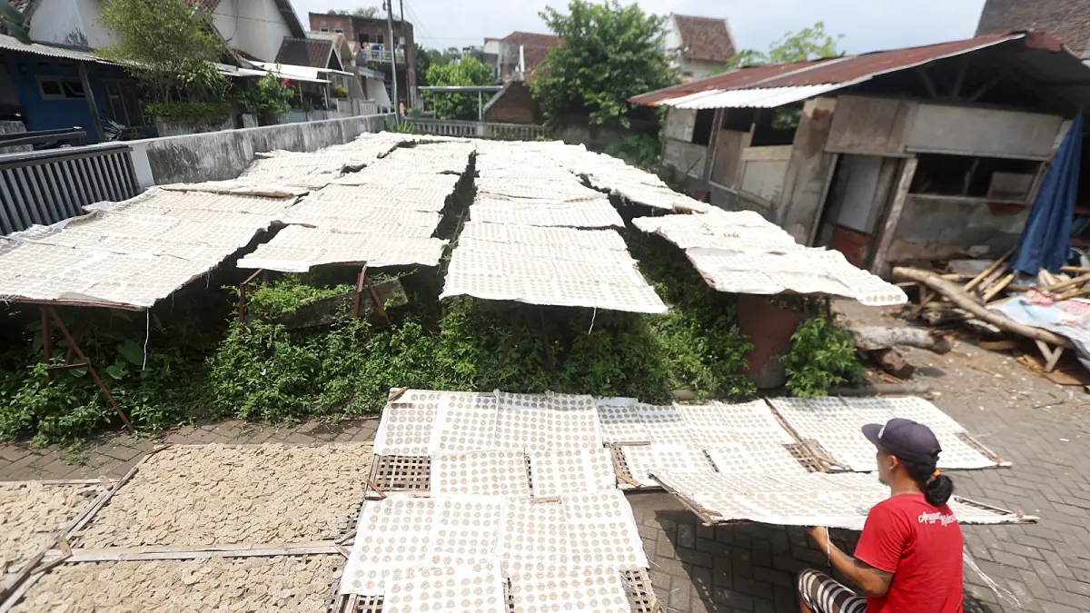 PILIH TAK NAIKKAN HARGA: Salah satu pegawai di pabrik kerupuk di Jalan Gadang Gang 21 B Nomor 3, Kelurahan Gadang, Kecamatan Sukun tengah menjemur kerupuk-kerupuk produksinya, kemarin. (Darmono / Radar Malang)