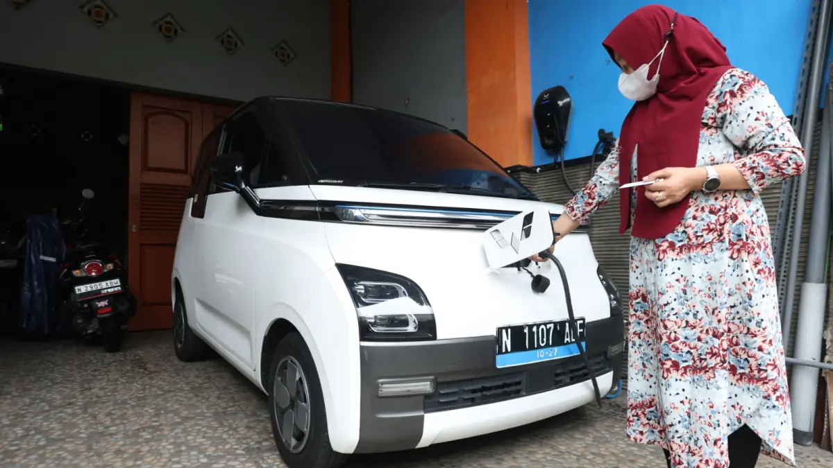BANYAK PEMINAT: Salah satu pengguna mobil listrik di Kota Malang memanfaatkan home charging untuk mengisi daya kendaraannya, kemarin. (Foto: Darmono)
