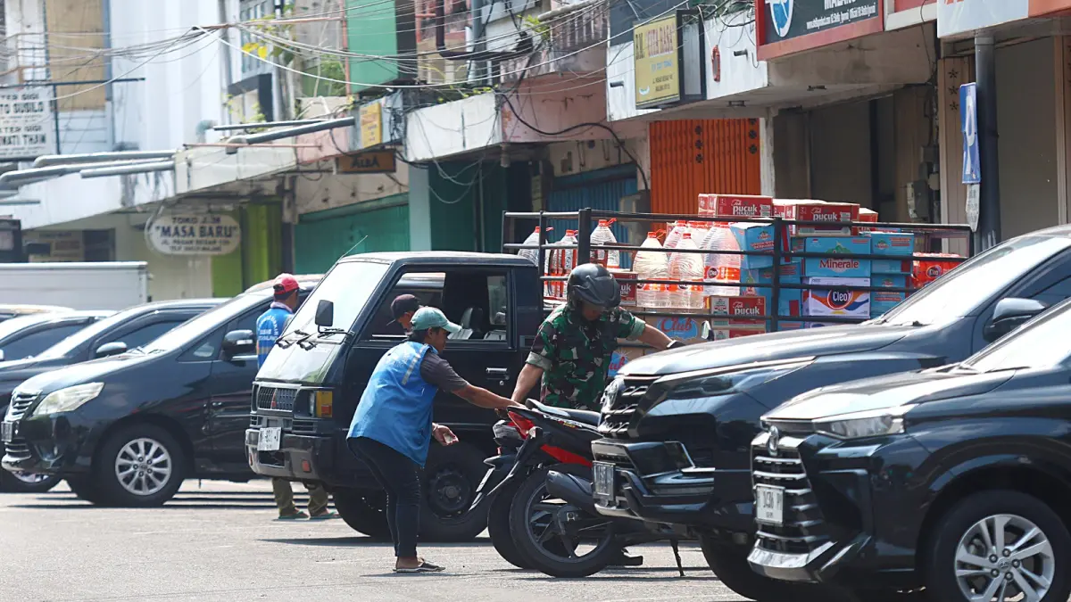 PEMKOT PUNYA DASAR HUKUM: Salah satu jukir di Jalan Pasar Besar membantu warga mengeluarkan motornya, kemarin (16/4). (DARMONO / RADAR MALANG)
