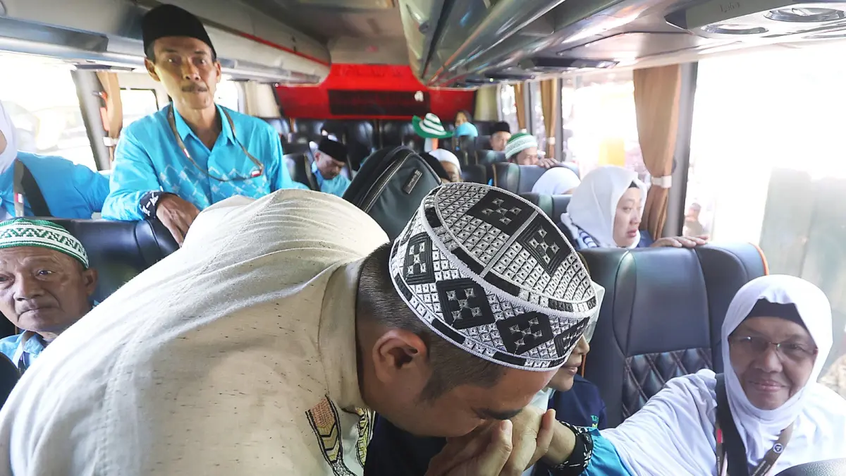 PENUH HARU: Salah satu warga mencium tangan ibunya yang berangkat ke Asrama Haji Embarkasi Surabaya dari Lapangan Ki Angmor, Blimbing, kemarin siang (24/4). (Darmono / Radar Malang)