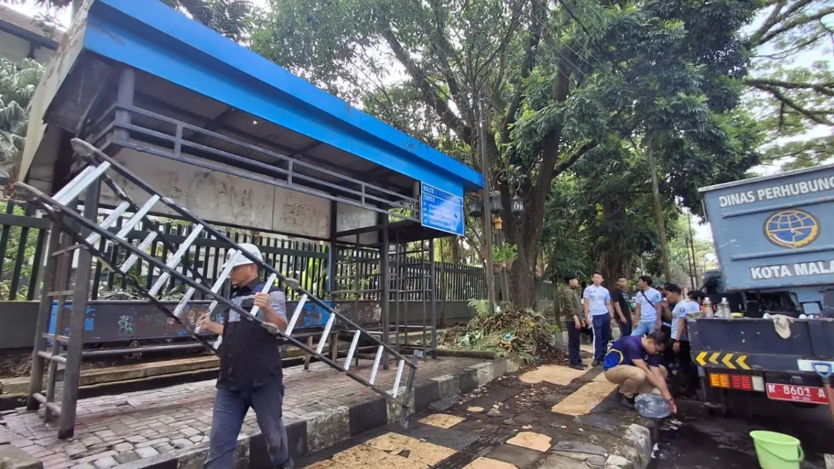 TERINSPIRASI: Petugas Dinas Perhubungan (Dishub) Kota Malang membersihkan halte di depan SMA Negeri 1 Malang, kemarin (27/4). (Nabila Amelia / Radar Malang) 