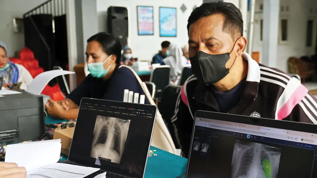 DIGENCARKAN: Dua warga mendapat penjelasan dari petugas terkait hasil skrining mobile x-ray yang digelar di Kantor Kelurahan Karangbesuki, kemarin (30/4).