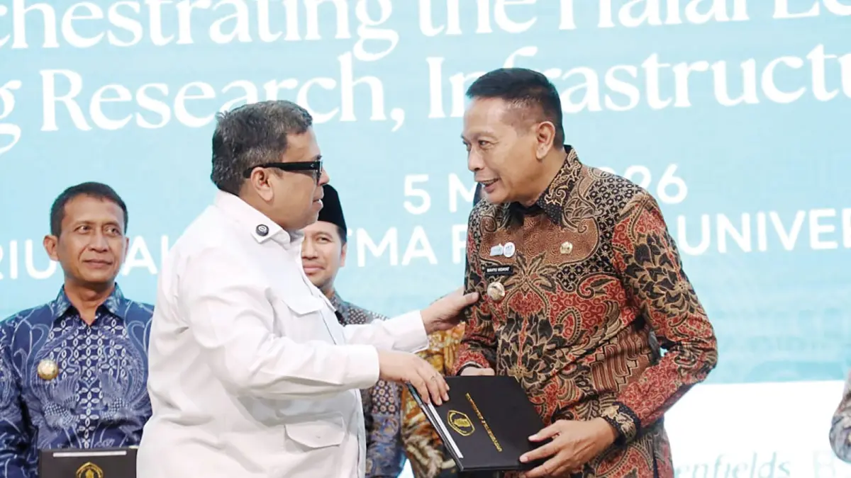 BENTUK KOMITMEN: Kepala Badan Penyelenggara Jaminan Produk Halal Haikal Hassan (kiri) menyerahkan penghargaan kepada Wali Kota Malang Wahyu Hidayat di Universitas Brawijaya (UB), Selasa lalu (5/5). (Prokompim Kota Malang For Radar Malang)