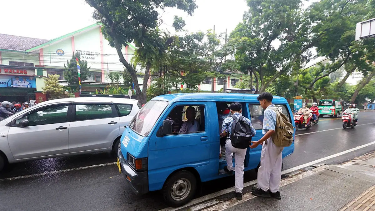 MASIH DIGODOK: Dua pelajar SMPN 20 Kota Malang naik angkot di Jalan Tumenggung Suryo, Blimbing untuk pulang, kemarin (8/5). (DARMONO / RADAR MALANG)