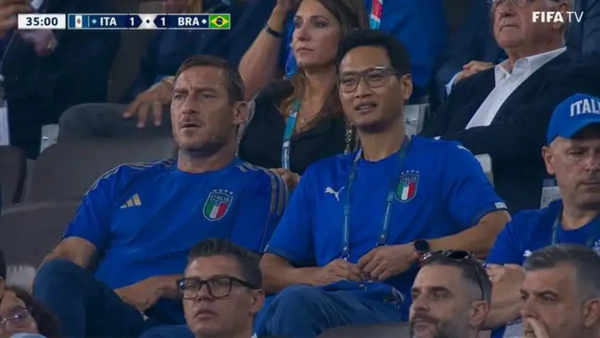 Foto hasil editan AI denban salah satu fans sepak bola menonton pertandingan bersama Fransesco Totti. (Istimewa)