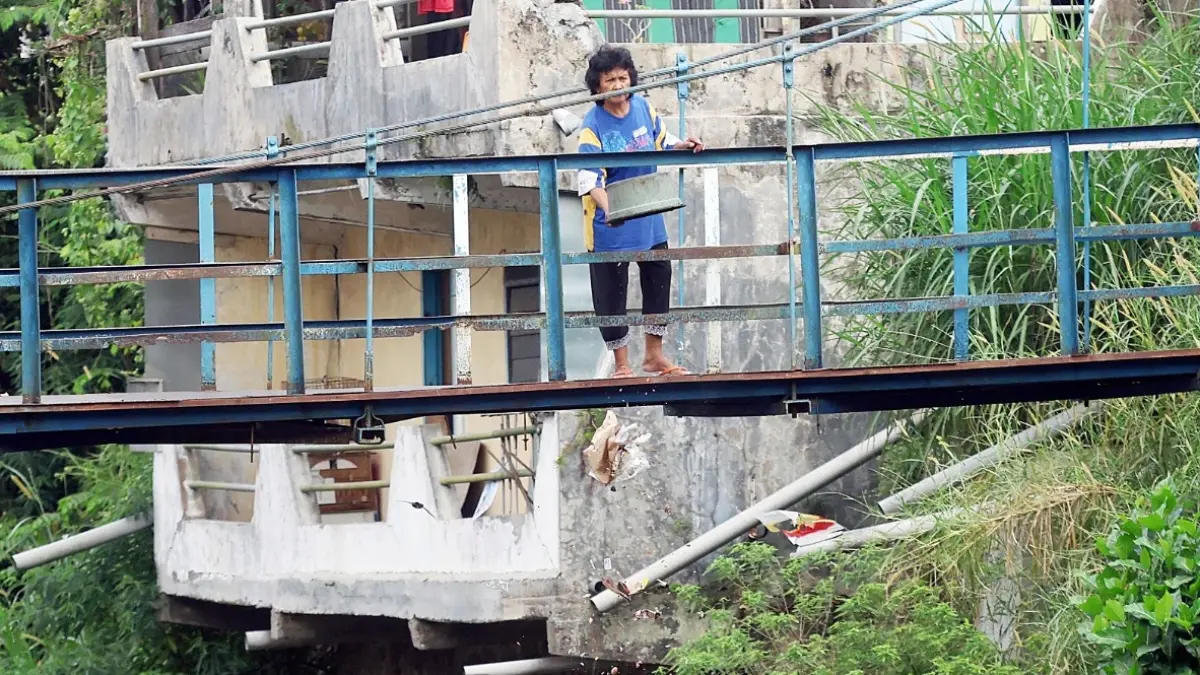 KEBIASAAN BURUK: Salah satu warga kedapatan membuang sampah dari jembatan gantung di kampung Muharto, kemarin (13/5). Pasokan sampah dari Kecamatan Kedungkandang dan Sukun bakal dimanfaatkan untuk mendukung PSEL. (Darmono/Radar Malang)