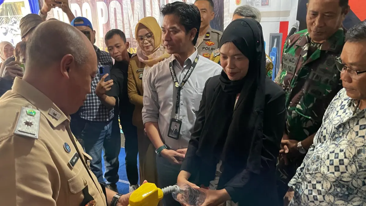 MULAI BEROPERASI: Kepala Diskopindag Kota Malang Eko Sya (kiri) mencoba langsung Pomindo dengan mengisi botol plastik dengan minyak goreng, kemarin. (Foto: Andika Satria Perdana/Radar Malang