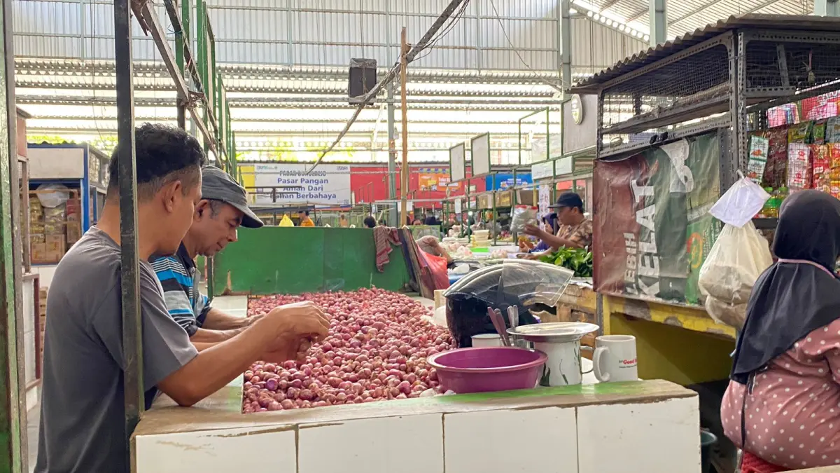 Pedagang di Pasar Bunulrejo memilah bawang merah. (Nabila Amelia/Radar Malang)