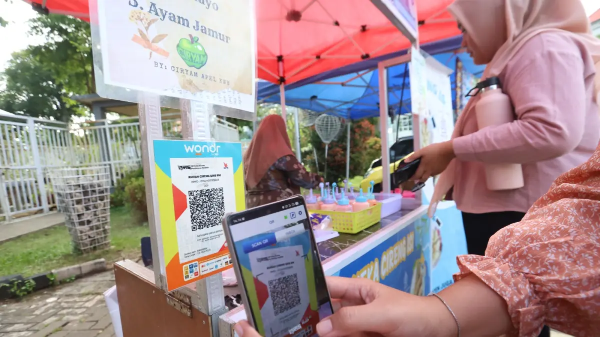 BERI KEMUDAHAN: Seorang pembeli memanfaatkan pembayaran digital dengan QRIS, pekan lalu. Sudah  ada 686.744 merchant yang menggunakan QRIS di area Malang. (Foto: Darmono/Radar Malang)