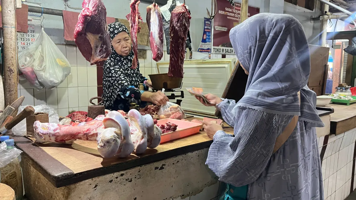 HARUS PUTAR OTAK: Seorang pedagang daging di Pasar Besar tengah melayani pembeli kemarin (26/5). Kenaikan harga daging sejak Idul Fitri diklaim para pedagang berdampak ke penjualan yang menurun. (Foto: NAHDIATUL AFFANDIAH/RADAR MALANG)