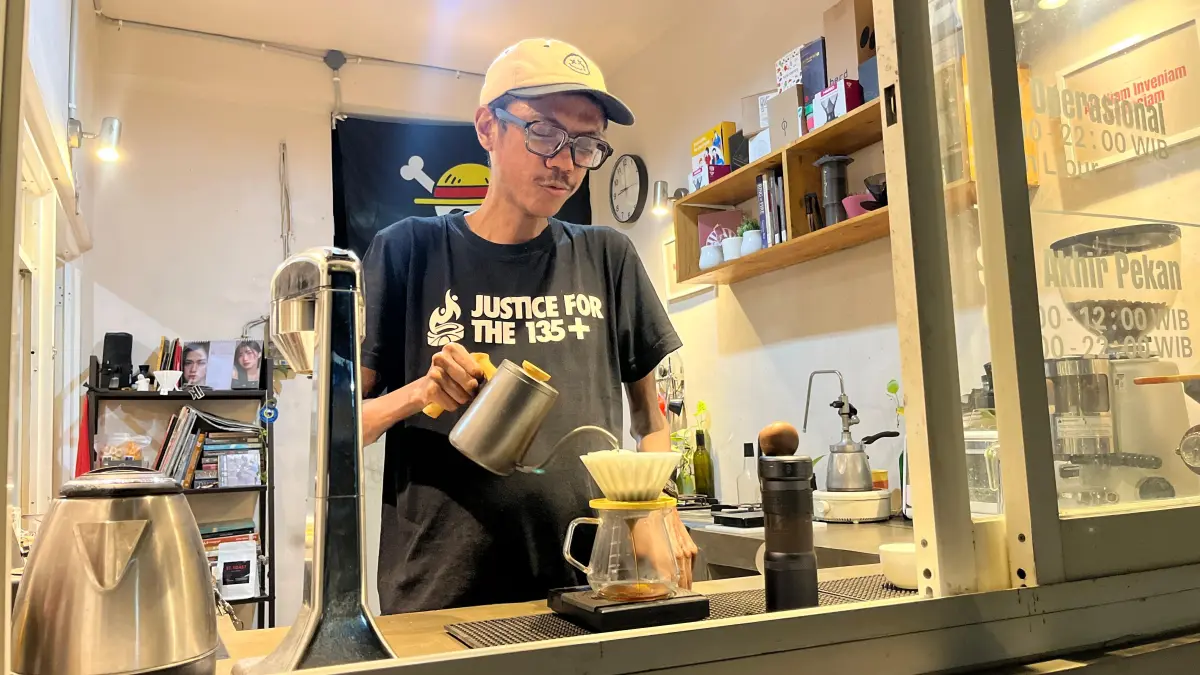 TAK PERNAH MENYERAH: Muhammad Nabiel menyeduh kopi untuk pelanggan di kedai Maeda yang dirintisnya kemarin malam. (Nahdiatul Affandiah/Radar Malang)
