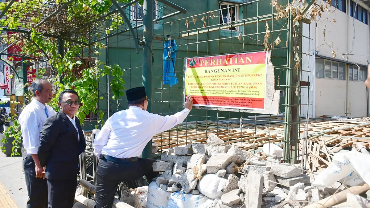 IZIN BELUM LENGKAP: Banner berisi peringatan ditempelkan Pemkot Malang di salah satu proyek bangunan di Jalan Semeru, kemarin (1/6). (Darmono/Radar Malang)