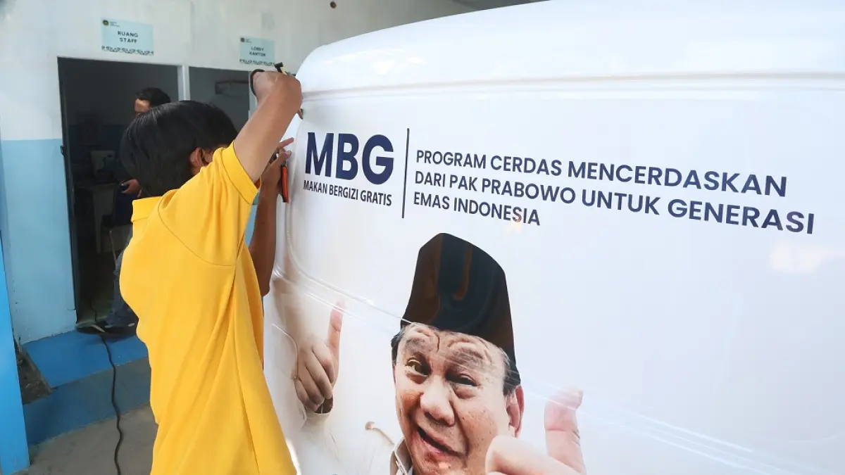 BELUM LENGKAPI IZIN: Salah satu pekerja SPPG di Kelurahan Gadang, Sukun, menempelkan sticker untuk mobil operasional MBG, beberapa waktu lalu. (Darmono/Radar Malang). 