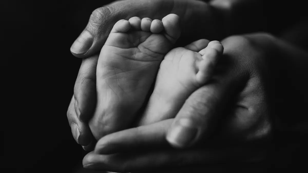 Orang tua menggenggam kaki bayi anaknya. (Magnific)