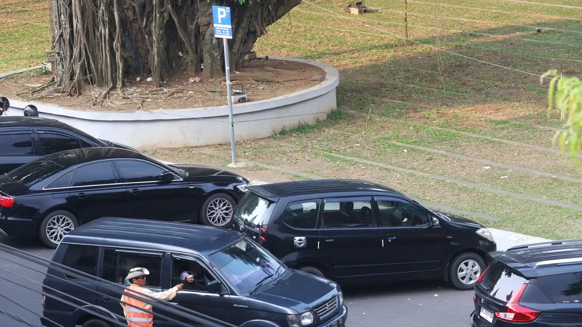 JANJI DIPERBAIKI: Salah satu jukir memberi aba-aba kepada pengendara di kawasan Alun-Alun Merdeka, kemarin (5/6). Sejumlah keluhan terkait operasional parkir sudah diterima Ombudsman RI. (Darmono/Radar Malang)