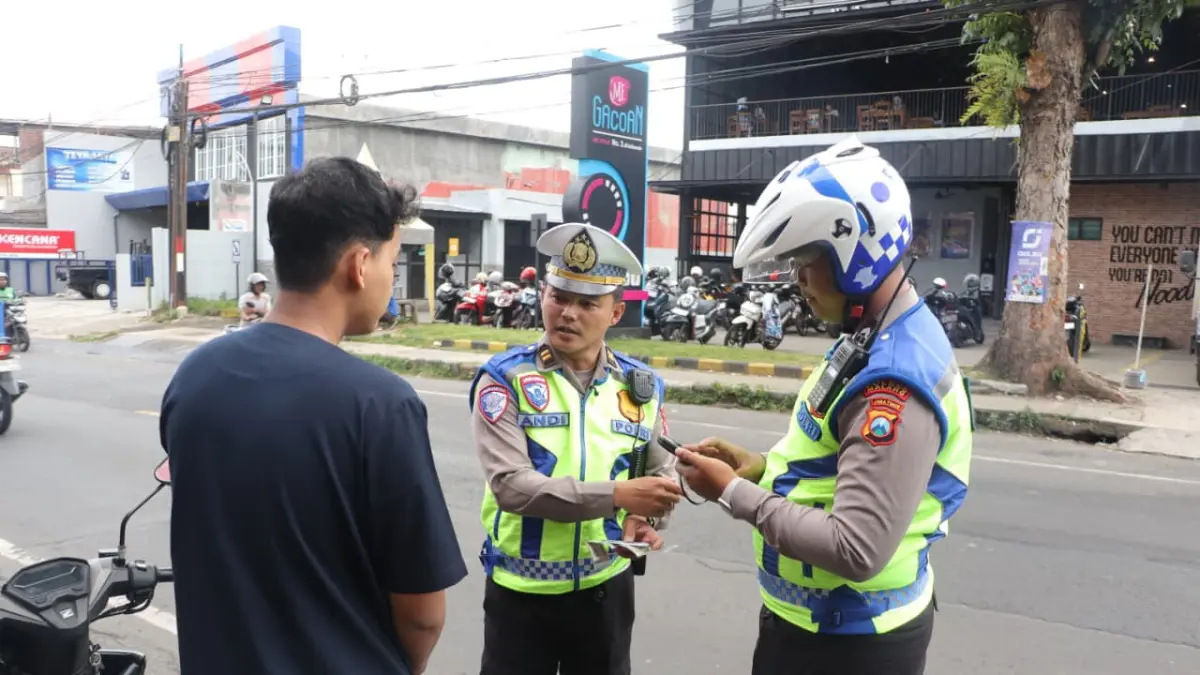 Dua petugas menghentikan seorang pengendara motor