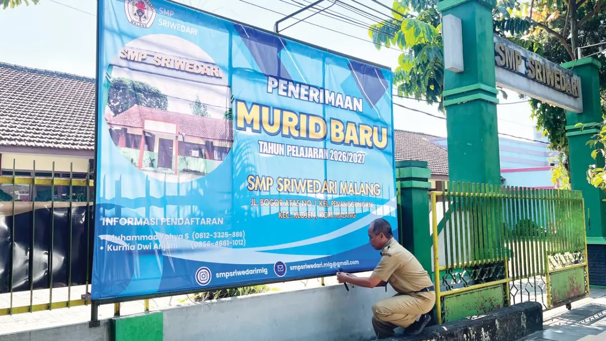 MENURUN: Salah satu guru di SMP Sriwedari memasang banner SPMB yang dibeli menggunakan dana Bosda, kemarin (9/6). (Nahdiatul Affandiah/Radar Malang)