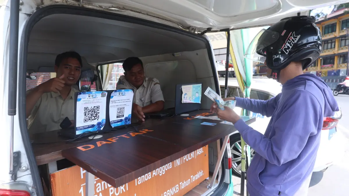 Seorang warga (kanan) memanfaatkan layanan Samsat Keliling di Jalan Bandung, Kota Malang, kemarin. (Darmono/Radar Malang)