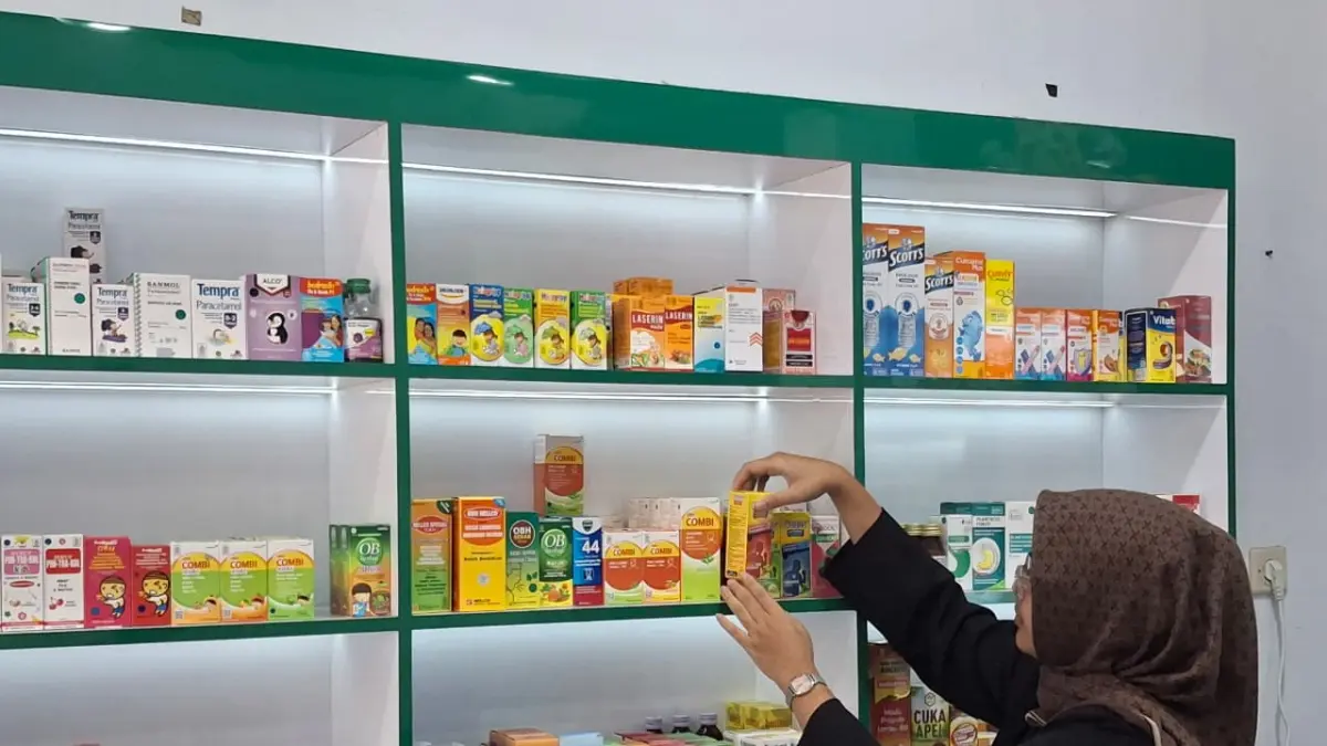 TERDAMPAK RUPIAH: Pemilik Apotek M-24 Meilani Rahma Putri tengah menata obat di etalase. Dia merasakan kenaikan harga sejumlah obat sejak dua bulan terakhir. (Foto: Nabila Amelia/Radar Malang)