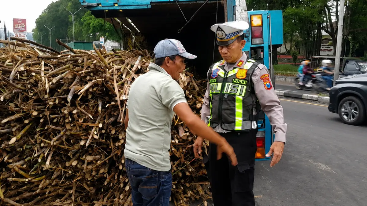 Personel Satlantas Polres Malang meminta keterangan kronologi tergulingnya truk tebu pada Jumat (12/6). (Satlantas Polres Malang)