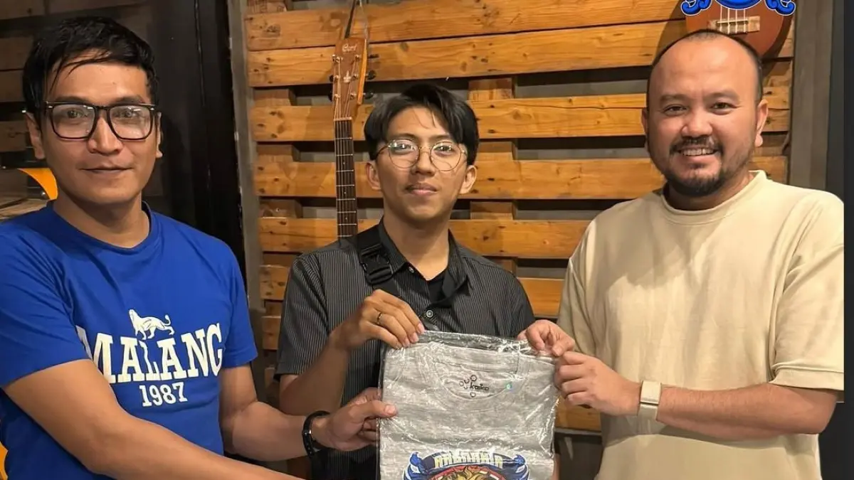 SIAP EMBAN TUGAS: Teddy Krisna (kiri) bersama Ali Rifki membagikan t-shirt kepada seorang Aremania beberapa waktu lalu.