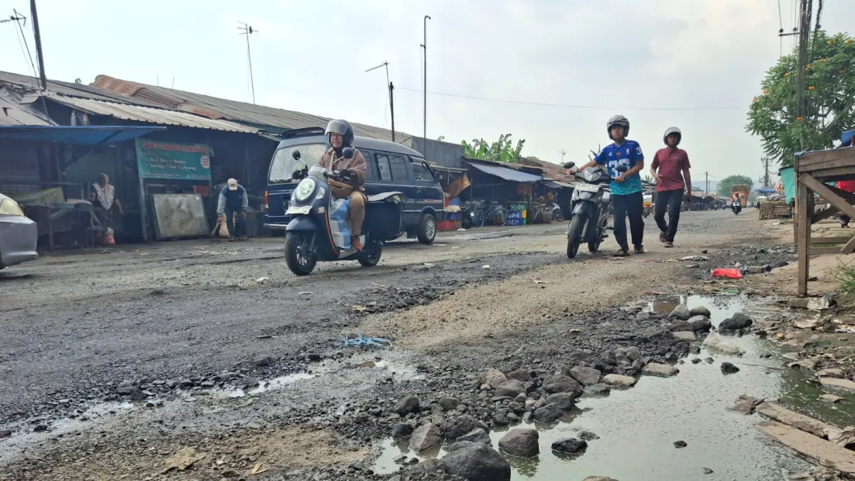 MENUNGGU LIMA TAHUN: Sejumlah pengendara harus menurunkan kecepatannya pada waktu melintas di  Jalan Pasar Induk Gadang. Sejumlah ruas jalan tergenang air dan tak mulus. (Foto: Nabila Amelia)